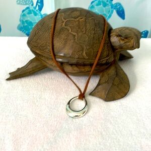 Brown leather cord necklace with silver oval pendant.